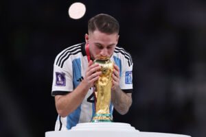 LUSAIL CITY, QATAR - DECEMBER 18: Alexis Mac Allister of Argentina kisses the FIFA World Cup Qatar 2022 Winner's Trophy during the FIFA World Cup Qatar 2022 Final match between Argentina and France at Lusail Stadium on December 18, 2022 in Lusail City, Qatar. (Photo by Clive Brunskill/Getty Images)